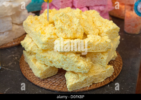 Gelbe Baiser Kuchen in Haufen auf dem Holz Stroh Teller Stockfoto