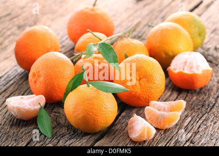 Mandarinen mit Blättern auf einem Holztisch. Stockfoto