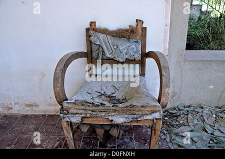 Sessel und Haufen Glasscherben auf der Veranda eines verlassenen Hauses zerrissen. Stockfoto