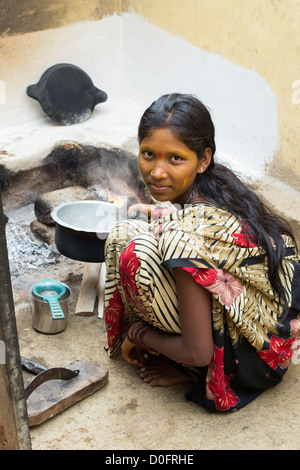 Junge Süd indische Frau kochende Milch auf einem offenen Feuer in ihrem ländlichen Dorf nach Hause. Andhra Pradesh, Indien Stockfoto