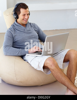 Junger Mann, hört gerne Musik über Kopfhörer, während der Arbeit von zu Hause aus. Stockfoto