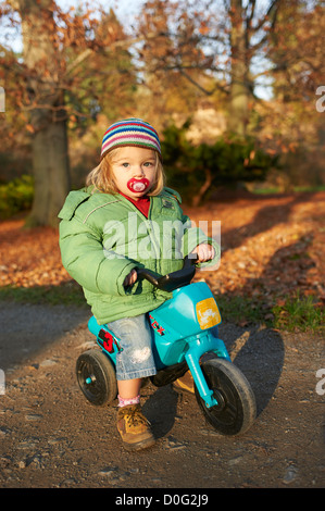 Einjähriges Mädchen reiten Kleinkind Kunststoff Trike (Dreirad) im Herbst park Stockfoto