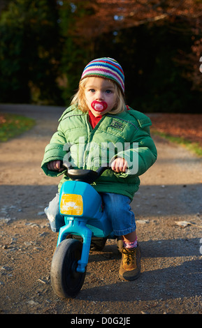 Einjähriges Mädchen reiten Kleinkind Kunststoff Trike (Dreirad) im Herbst park Stockfoto