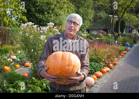 Porträt stolzer Mann mit großen Kürbis in einem Garten mit Kürbissen im Klok und Peel Museum in Asten in den Niederlanden Stockfoto