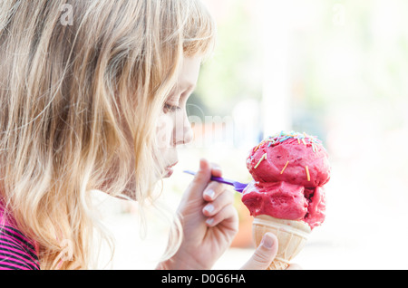 Kleines Mädchen isst große Eis im Park. Profilbildnis mit selektiven Fokus Stockfoto