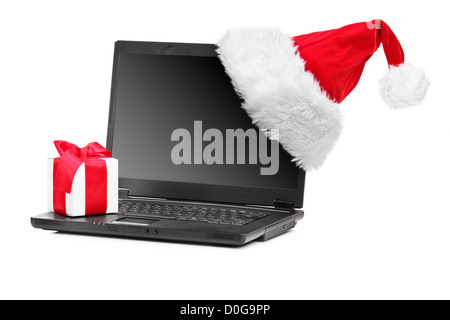 Studioaufnahme Weihnachtsmütze und Geschenk auf einem Laptop isoliert auf weißem Hintergrund Stockfoto