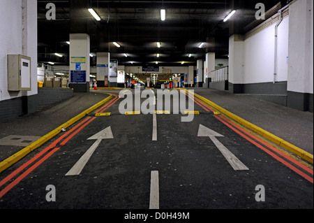 Leerer Blick und dunklen Parkplatzeingang mit großen weißen Pfeile am Boden weisen den Weg in Stockfoto