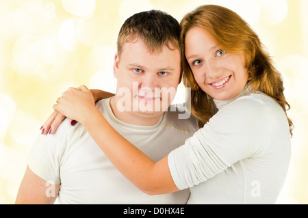 Ein attraktives junges Paar posieren. Sie sind weiß mit gelben Lichter im Hintergrund tragen. Stockfoto