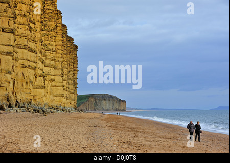 Wanderer zu Fuß am Strand von East Cliff, gemacht aus Sandstein, in der Nähe von West Bay entlang der Jurassic Coast, Dorset, Südengland, UK Stockfoto