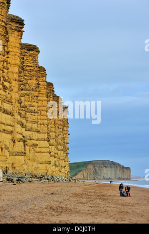 Wanderer zu Fuß am Strand von East Cliff, gemacht aus Sandstein, in der Nähe von West Bay entlang der Jurassic Coast, Dorset, Südengland, UK Stockfoto