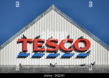 Tauben in der Sonne auf dem Dach eines Tesco Stores Schlafplatz. Stockfoto