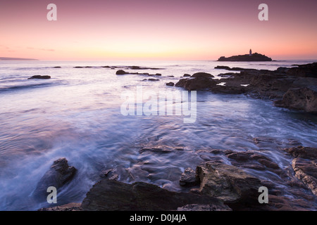 Kollision mit Felsen bei Sonnenuntergang, Godrevy Leuchtturm, Küste Cornwalls Meerwasser Stockfoto