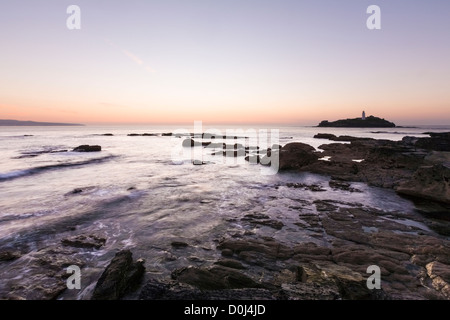 Kollision mit Felsen bei Sonnenuntergang, Godrevy Leuchtturm, Küste Cornwalls Meerwasser Stockfoto