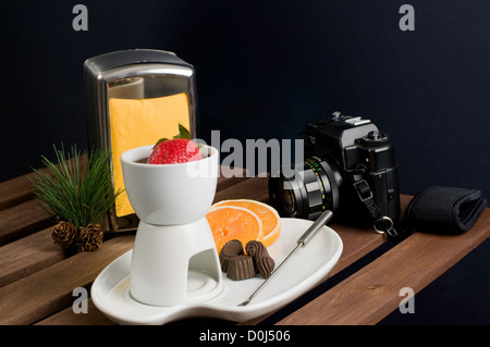 Straberry tauchte in Fondue Weißware-Fondue-Set mit Kamera auf Holztisch Stockfoto