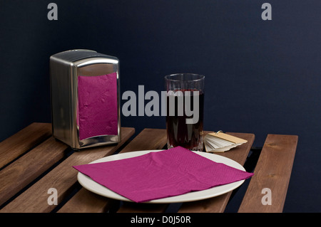 Serviette auf Porzellanteller und Saft im Glas auf Holztisch Stockfoto