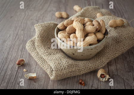 Handvoll Erdnüsse in einer Schüssel auf Holztisch Stockfoto