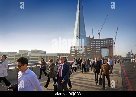 Pendler, die zu Fuß zur Arbeit über London Bridge mit dem Shard Gebäude im Hintergrund. Stockfoto