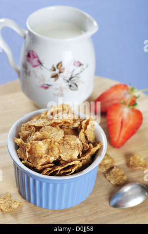 Leckere und nahrhafte Kleie Flocken Getreide in blaue Schale mit Erdbeeren auf Holzbrett Stockfoto