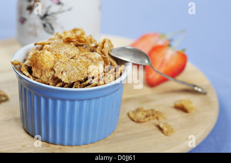 Leckere und nahrhafte Kleie Flocken Getreide in blaue Schale mit Erdbeeren auf Holzbrett Stockfoto