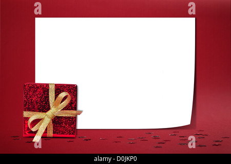 Weihnachten Blatt Papier mit kleinen Geschenk auf rotem Grund Stockfoto