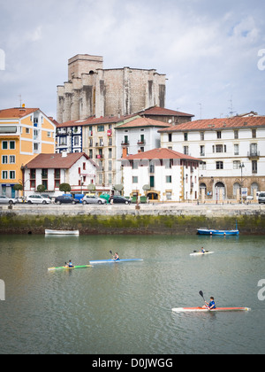 Menschen, Kajakfahren in der Nähe von Zumaia, Guipuzkoa, im Norden Spaniens. Die baskischen Stil gotische Kirche von San Pedro steht im Hintergrund Stockfoto