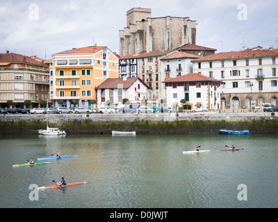 Menschen, Kajakfahren in der Nähe von Zumaia, Guipuzkoa, im Norden Spaniens. Die baskischen Stil gotische Kirche von San Pedro steht im Hintergrund Stockfoto