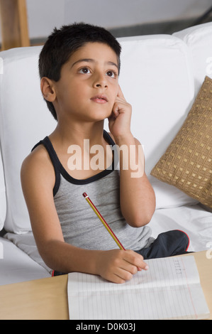 Junge auf einem Sofa sitzt und denkt Stockfoto