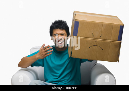 Mann hält einen Karton mit einem Smiley-Gesicht und lachen Stockfoto