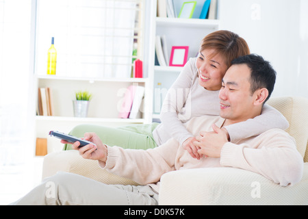 Porträt von asiatischen Brautpaar auf Couch sitzen und vor dem Fernseher zusammen Stockfoto