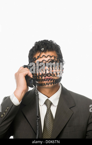 Geschäftsmann am Telefon mit seinem Gesicht fallenden Telefonkabel Stockfoto