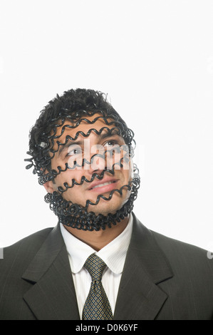 Nahaufnahme von einem Geschäftsmann Gesicht bedeckt mit Telefonkabel Stockfoto