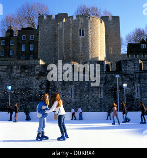 Jugendliche Eislaufen auf den Burggraben Eislaufbahn Tower von London mit Blick auf den Weißen Turm in der Stadt von London England UK KATHY DEWITT Stockfoto