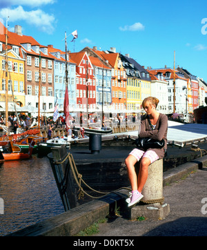 Eine junge Frau sitzt am Kanal am Nyhavn Hafen in Copenhagen Dänemark KATHY DEWITT Stockfoto