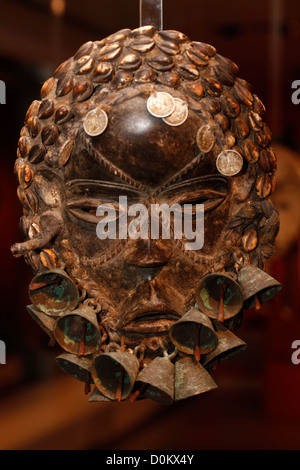 Eine Stammesmaske aus geschnitztem Holz, die mit Glocken und coins.used in einer Vielzahl von Zeremonien und Ritualen innerhalb der Dan, Wee, auch bekannt als Wè oder Guéré-Kultur, verziert ist und sich im westlichen Côte d'Ivoire und Liberia in Afrika konzentriert Stockfoto