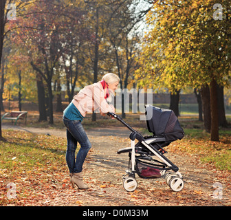 Junge Mutter ihr Kind in einem Kinderwagen zu betrachten Stockfoto