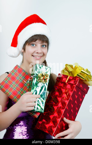 attraktives Mädchen in eine Weihnachtsmütze mit einem Bündel von Geschenk-Boxen Stockfoto