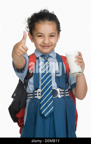 Schulmädchen Daumen hält ein Glas Milch und zeigen Zeichen Stockfoto