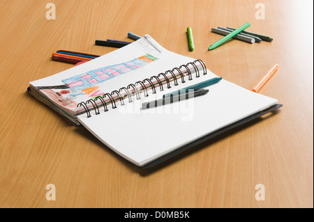 Nahaufnahme von einem Notebook und Buntstiften auf einem Schreibtisch Stockfoto