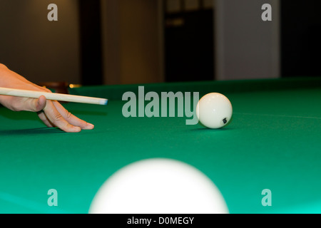 Vierw Bild einer männlichen Hand balancieren ein Stichwort und Schlange mit der weißen Kugel während des Spiels einer Partie Snooker auf einer grünen Filz-Tabelle abgeschnitten. Stockfoto