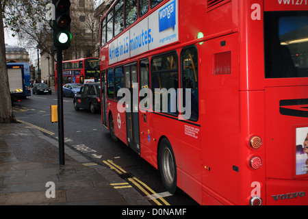 Roten London Doppeldeckerbus vorbei an grünen Ampeln, andere Verkehrsteilnehmer im Hintergrund Stockfoto