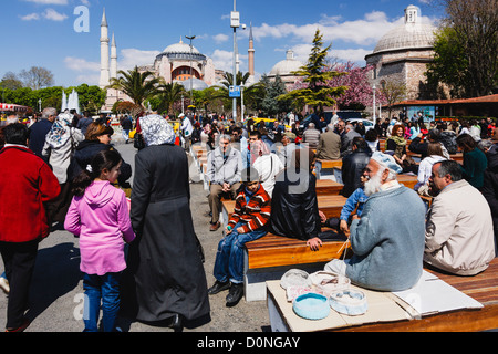 Viele türkische Menschen sitzen und gehen im Sultanahmet-Park mit Haghia Sophia im Hintergrund. Istanbul, Türkei Stockfoto