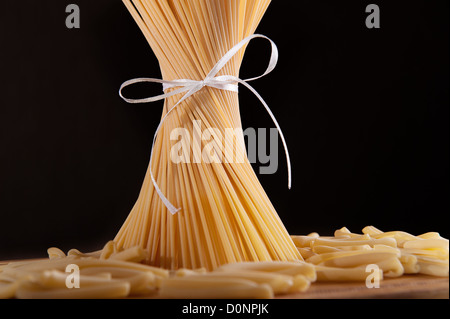Band gebunden Haufen Spaghetti Nudeln auf schwarzem Hintergrund Stockfoto