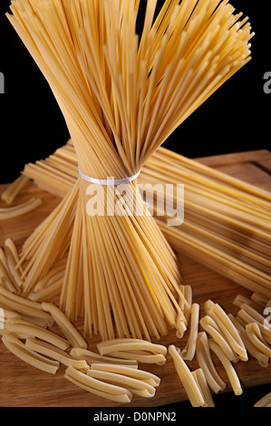 Band gebunden Haufen Spaghetti Nudeln auf schwarzem Hintergrund Stockfoto