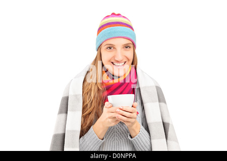 Lächelnde Frau bedeckt mit Decke halten einer Teetasse isoliert auf weißem Hintergrund Stockfoto