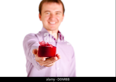 Junger Mann bietet Ihnen Geschenk und Blick in die Kamera, isoliert auf weißem Hintergrund Stockfoto