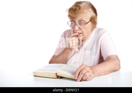 alte Frau in Gläsern liest das Buch Stockfoto