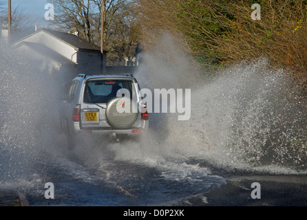 Auto durch stehendes Wasser auf der überfluteten Straße, Cumbria, England UK Stockfoto
