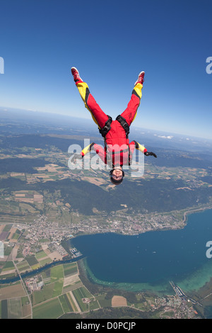 Fallschirmspringer-Mädchen ist Spaß durch fliegen in einem Kopf nach unten in den blauen Himmel über einer schönen Seengebiet. Stockfoto