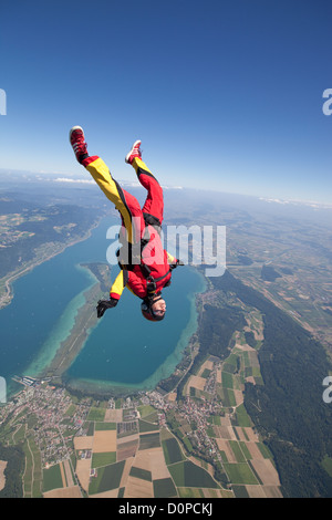 Fallschirmspringer Mädchen fliegt in einer kopfüber-Position über eine wunderschöne Seengebiet. Sie ist Spaß und fallen mit einer Geschwindigkeit von 125 km/h Stockfoto