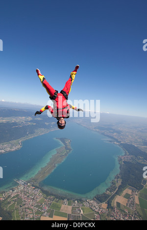 Fallschirmspringer Mädchen fliegt in einer kopfüber-Position über eine wunderschöne Seengebiet. Sie ist Spaß und fallen mit einer Geschwindigkeit von 125 km/h Stockfoto